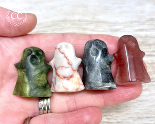 A hand holding four crystal Ghost carvings in various crystal types