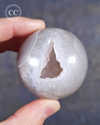 A hand holding an Agate Geode Sphere