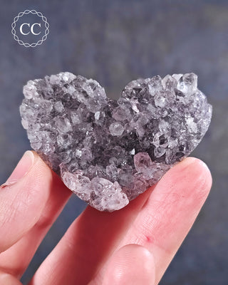 A hand holding an Amethyst Cluster Heart from Brazil