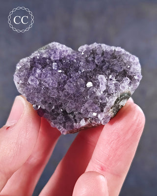 A hand holding an Amethyst Cluster Heart from Brazil