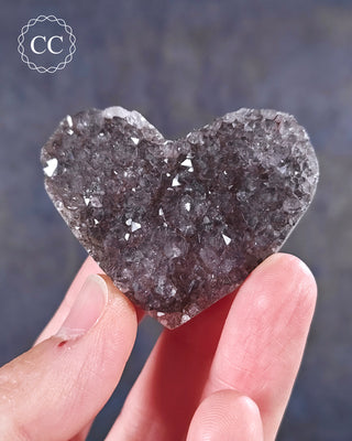 A hand holding an Amethyst Cluster Heart from Brazil