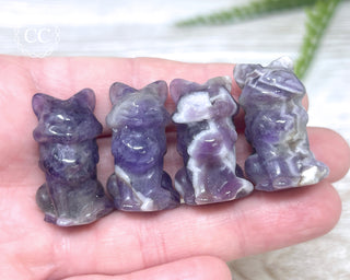 A hand holding 4 Amethyst Fox Carvings 