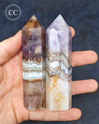 A hand holding 2 Amethyst with Agate Towers from Mexico 