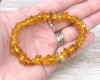A hand holding one Baltic Amber gem chip beaded stretch bracelet 