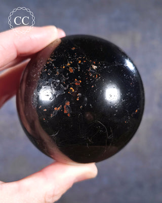A hand holding a Black Tourmaline Sphere from Madagascar