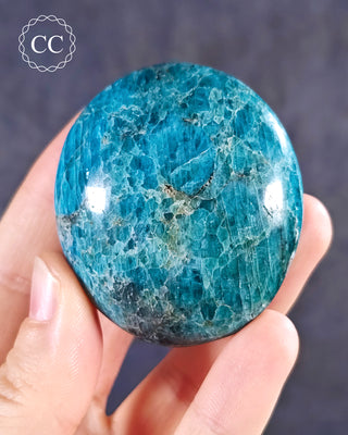 A hand holding a Blue Apatite Chunky palmstone from Madagascar