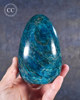 A hand holding a Blue Apatite cut base freeform from Madagascar
