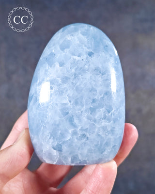 A hand holding a Blue Calcite freeform from Madagascar