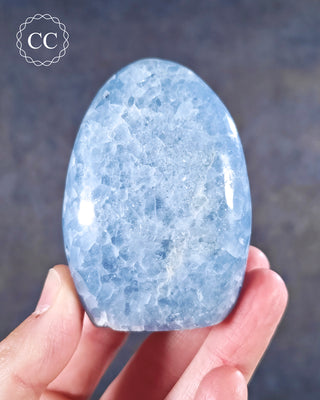 A hand holding a Blue Calcite freeform from Madagascar