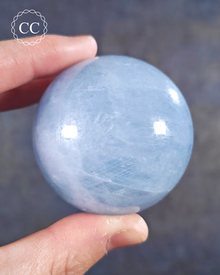 A hand holding a Blue Calcite Sphere from Madagascar