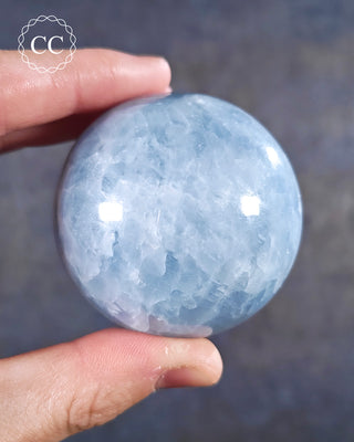A hand holding a Blue Calcite Sphere from Madagascar