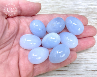 A hand holding 8 Blue Chalcedony Mini Eggs 