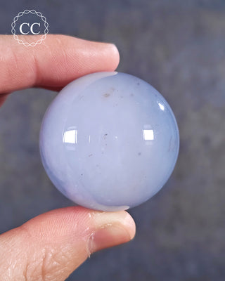 A hand holding a Blue Chalcedony Sphere
