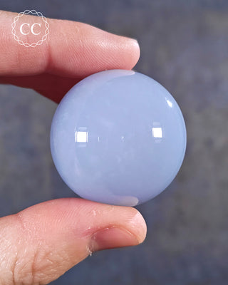 A hand holding a Blue Chacedony Sphere