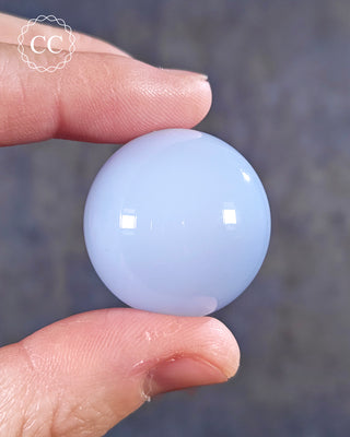 A hand holding a Blue Chalcedony Sphere