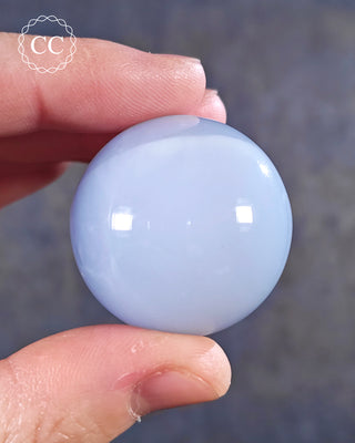 A hand holding a Blue Chalcedony Sphere