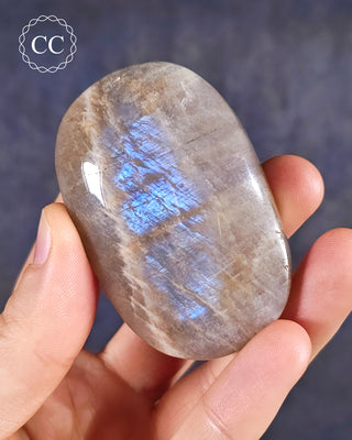 A hand holding a Blue Moonstone Palmstone