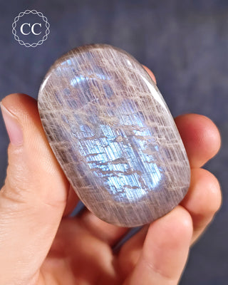 A hand holding a Blue Moonstone Palmstone