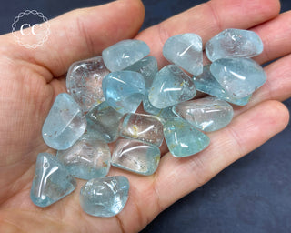 A hand holding a selection of Blue Topaz tumbled crystals 