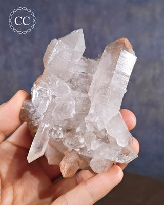 Quartz Cluster from Brazil in hand, on a blue background