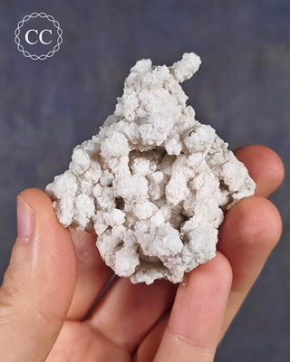 A hand holding a Calcite specimen from Bulgaria with a secondary growth coating of Calcite over the main Quartz body