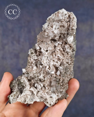 A hand holding a Calcite specimen with Marcasite inclusions  from the Linwood Mine, Buffalo, Iowa