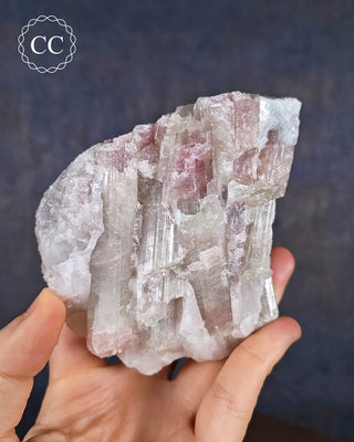A hand holding soft candy coloured, ombre Tourmaline specimen from Brazil