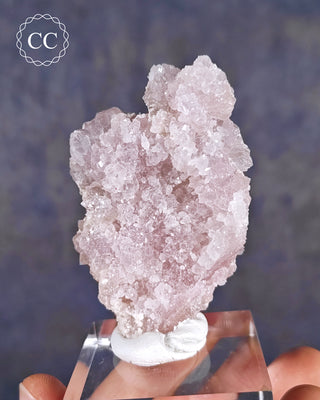 A clear display base showcasing a rare Canga Rosa specimen, also known as Crystallised Rose Quartz 