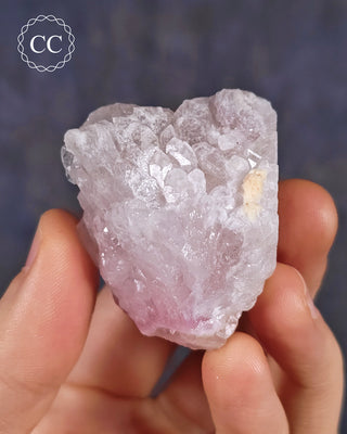 A hand holding arare Canga Rosa specimen, also known as Crystallised Rose Quartz specimen 