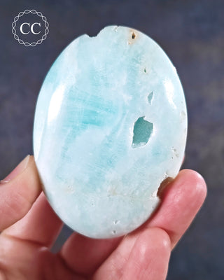A hand holding a Caribbean Calcite chunky palmstone