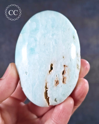 A hand holding a Caribbean Calcite chunky palmstone