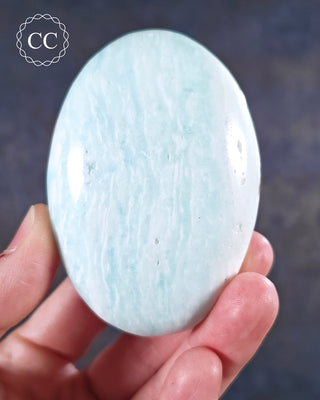 A hand holding a Caribbean Calcite chunky palmstone