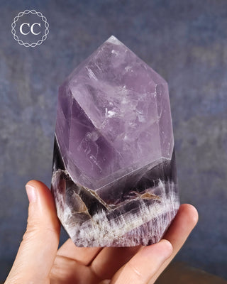 A hand holding a Chevron Amethyst Tower from Brazil 