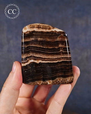 A hand holding a Chocolate Calcite freestanding freeform from Pakistan,