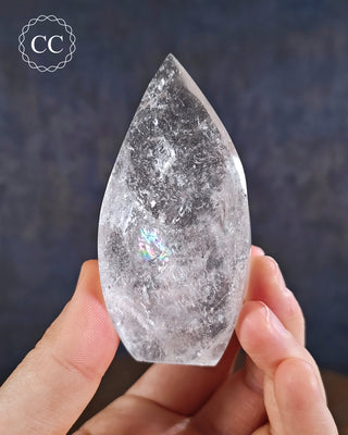 Clear Quartz Flame in hand on blue background