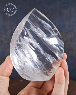 Clear Quartz Flame in hand on blue background