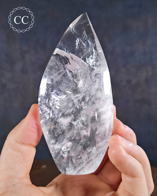 Clear Quartz Flame in hand on blue background
