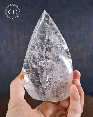 Clear Quartz Flame in hand on blue background