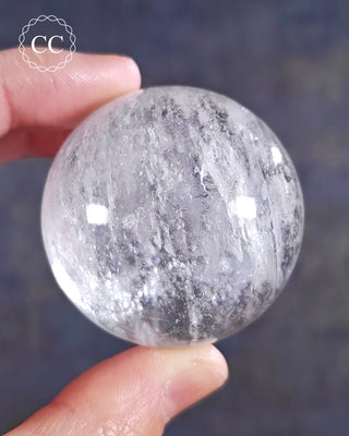 A hand holding a Clear Quartz sphere from Madagascar