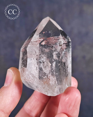 Fingers holding a Clear Quartz Tower from Brazil 