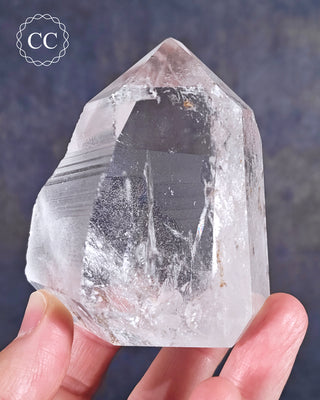 A Brazilian semi Polished Clear Quartz tower help up by fingers