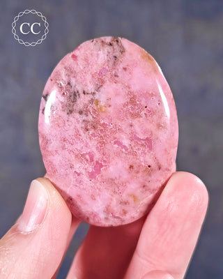 A hand holding a flat style Cobalto Calcite Palmstone
