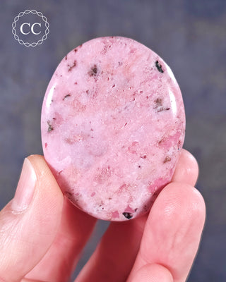 A hand holding a flat style Cobalto Calcite Palmstone