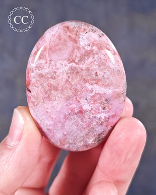 A hand holding a flat style Cobalto Calcite Palmstone
