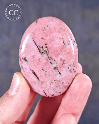 A hand holding a flat style Cobalto Calcite Palmstone