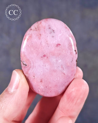 A hand holding a flat style Cobalto Calcite Palmstone