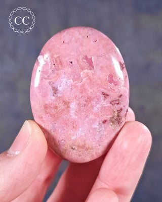 A hand holding a flat style Cobalto Calcite Palmstone