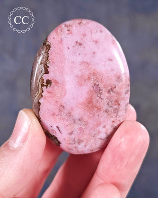A hand holding a flat style Cobalto Calcite Palmstone