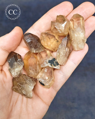 Congo Citrine Crystal Points in hand on a blue background