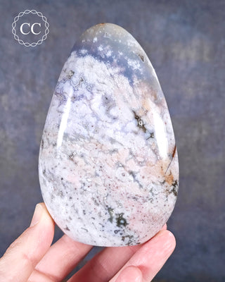 A hand holding a Cosmic Jasper Freeform from Madagascar